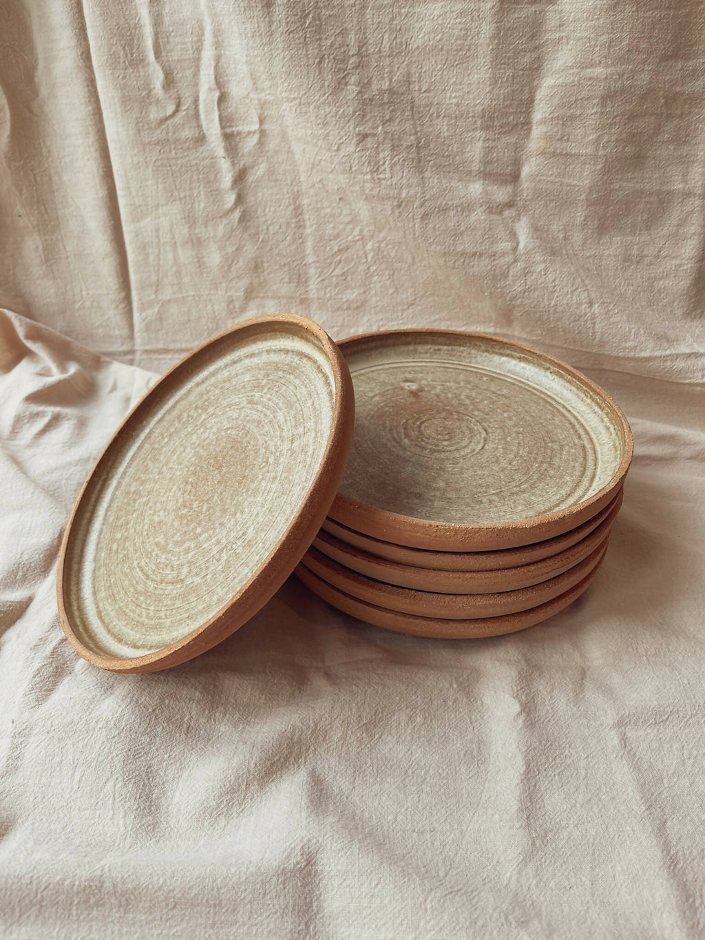 Assiettes creuses en céramique beige à bord brun, pile avec une assiette soulevée