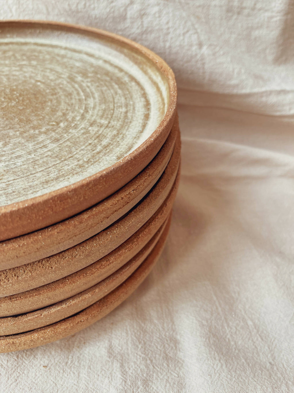Assiettes creuses en céramique beige à bord brun, gros plan sur pile superposée
