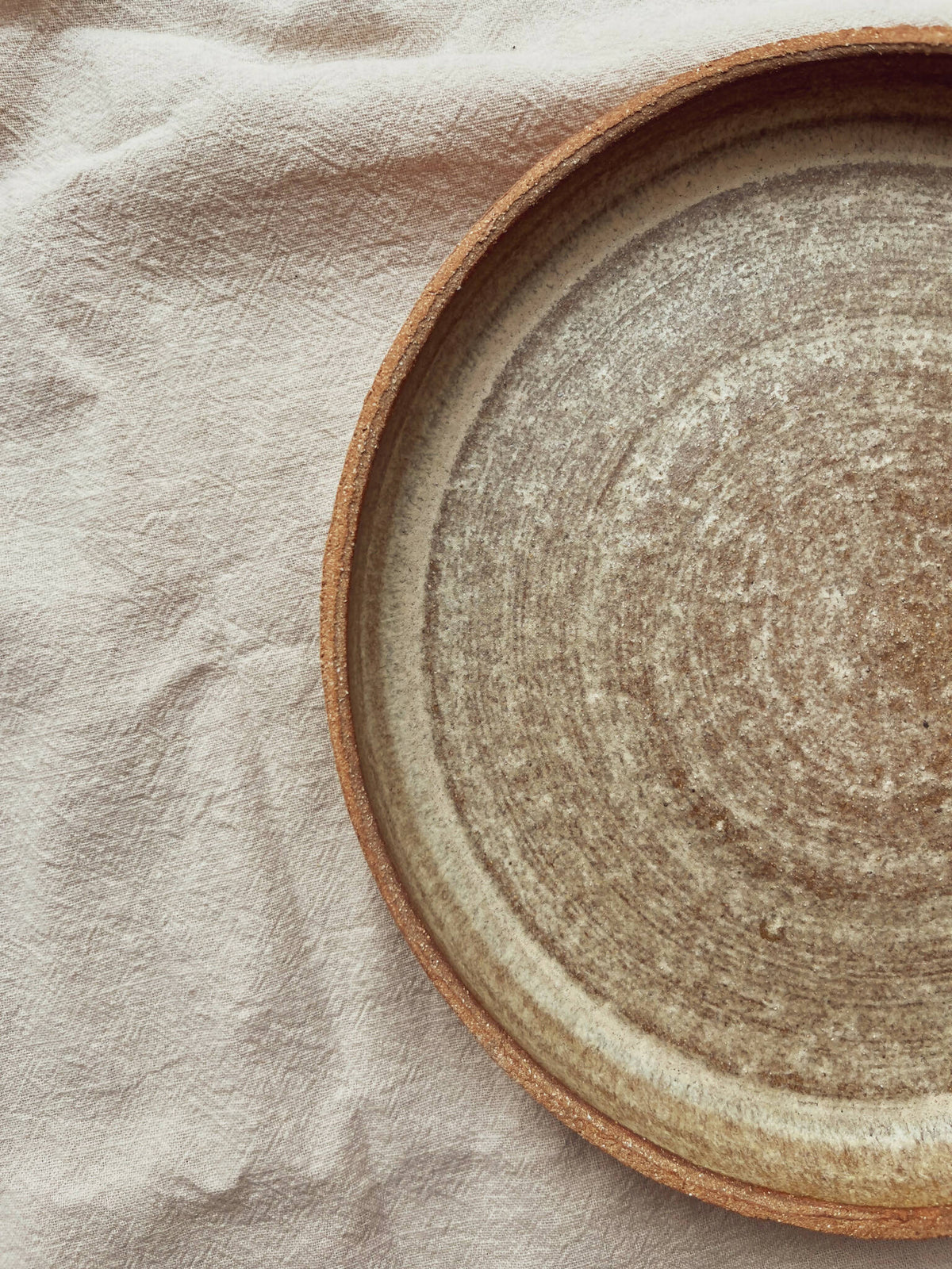 Assiette creuse en céramique beige, bord brun et intérieur texturé, gros plan