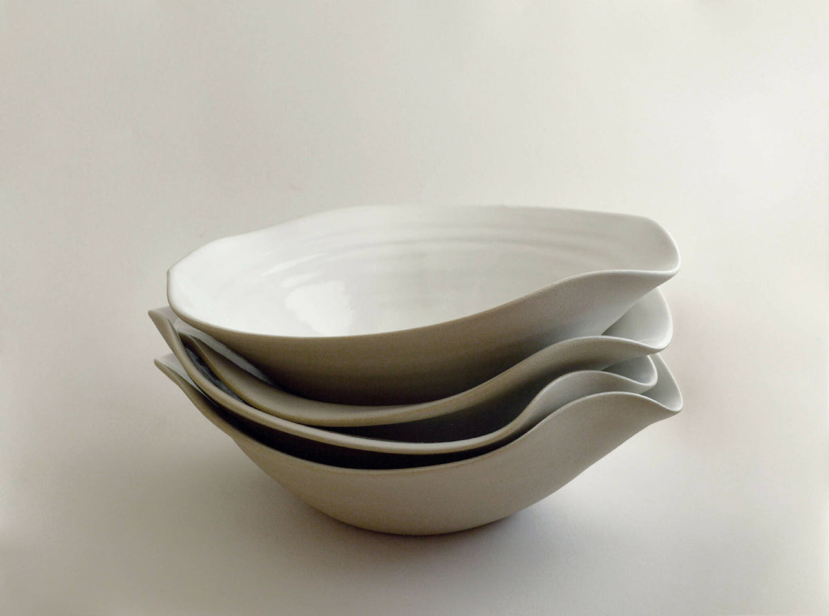 Lot d’assiettes creuses en céramique blanche empilées, bord ondulé
