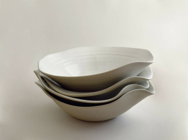 Lot d’assiettes creuses en céramique blanche empilées, bord ondulé
