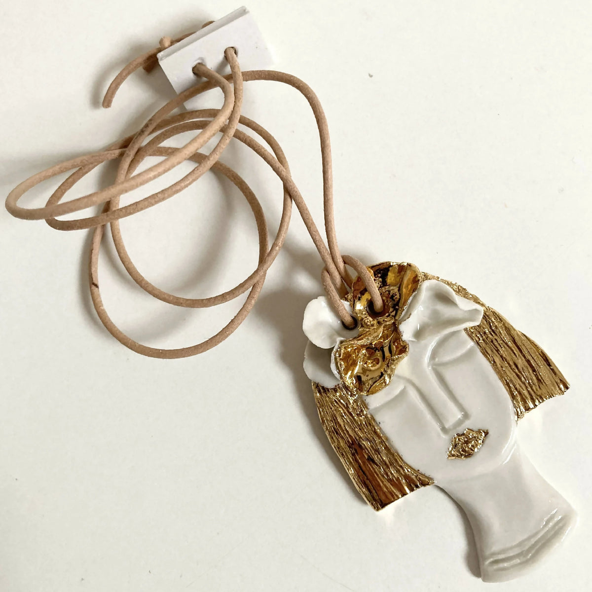 Pendentif buste blanc et doré à franges, cordon en cuir beige et attache blanche