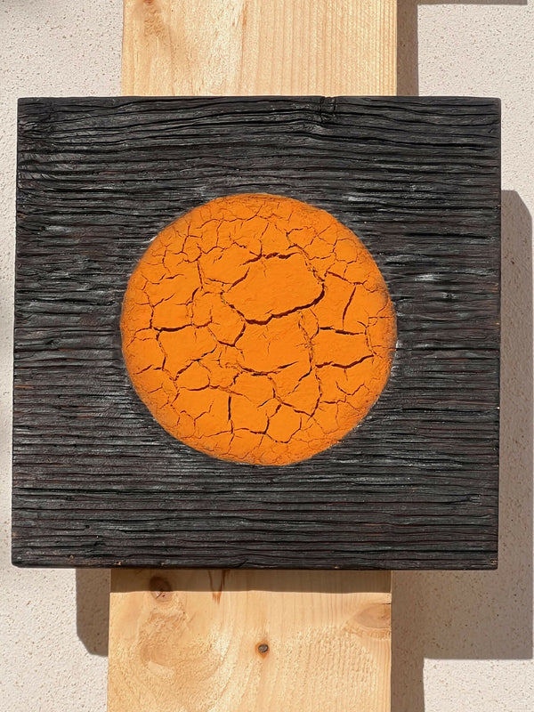 Panneau en bois sombre avec disque orange craquelé