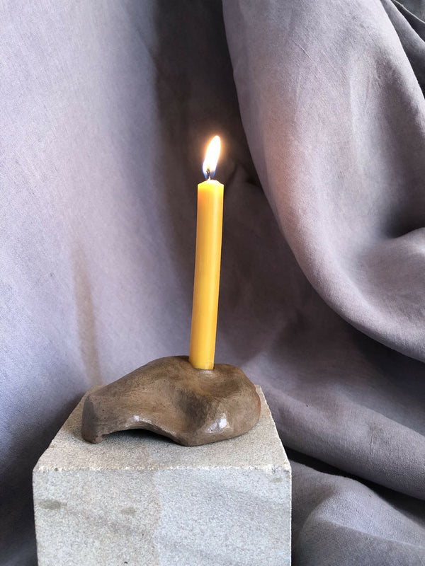 Mini bougeoir en pierre beige, bougie jaune sur socle carré