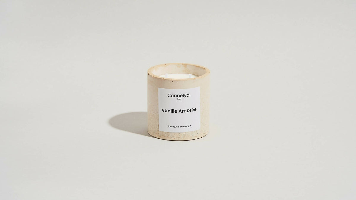Bougie parfumée Cannelya dans un pot beige texturé, étiquette Vanille Ambrée