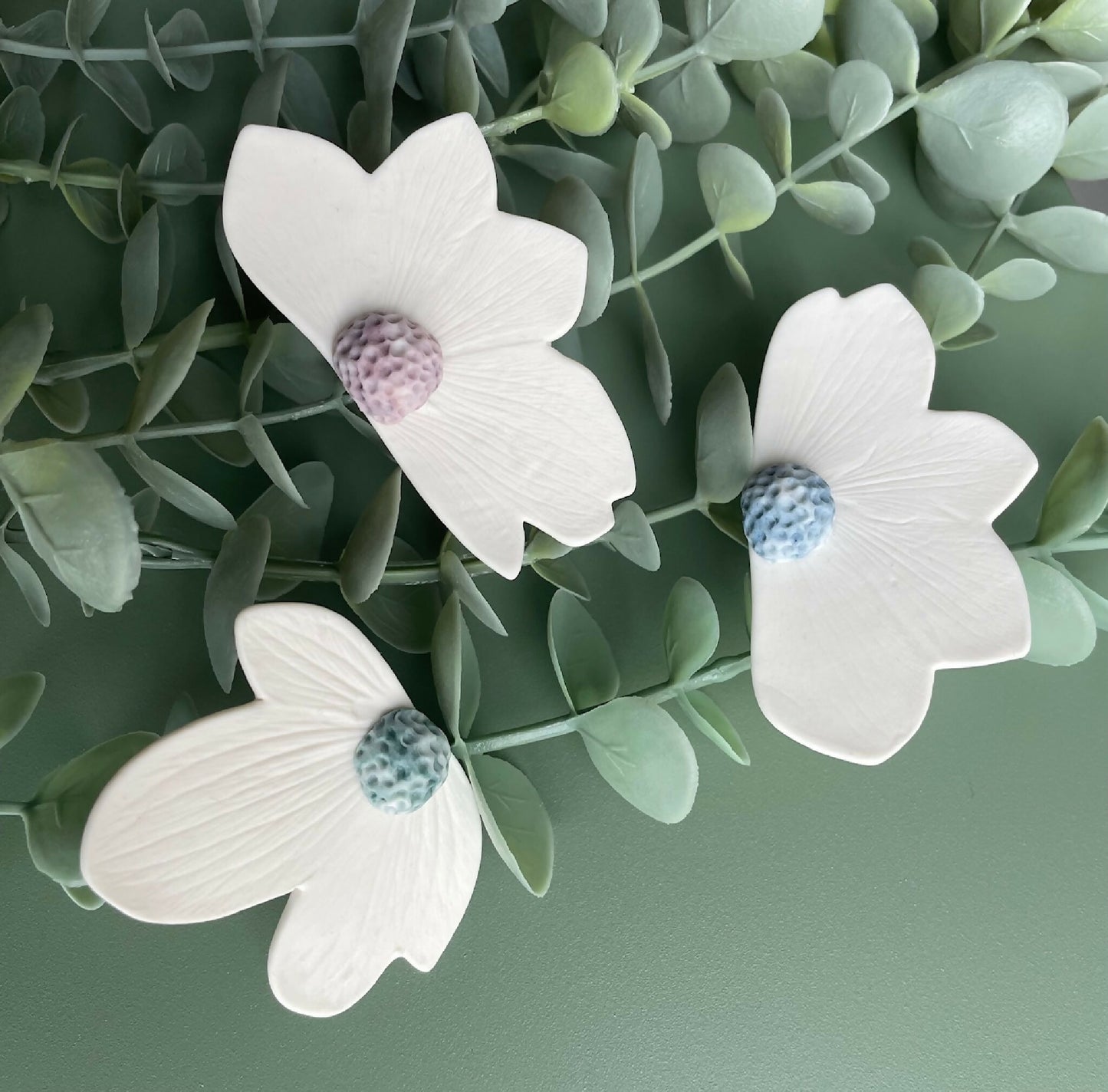 Broches florales en porcelaine aimantée, pétales blancs, centres bleu et violet.