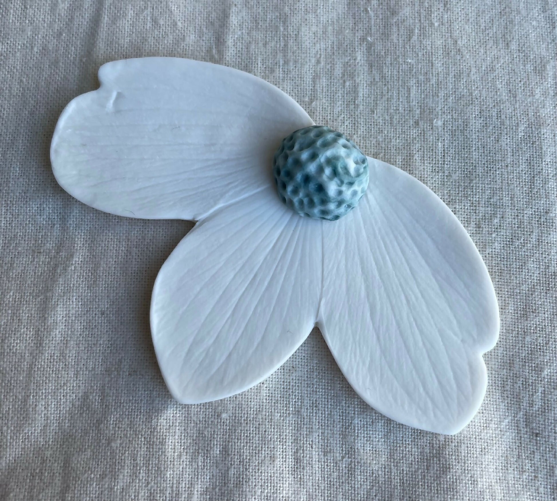 Broche florale en porcelaine aimantée, pétales bleu clair, centre bleu texturé.