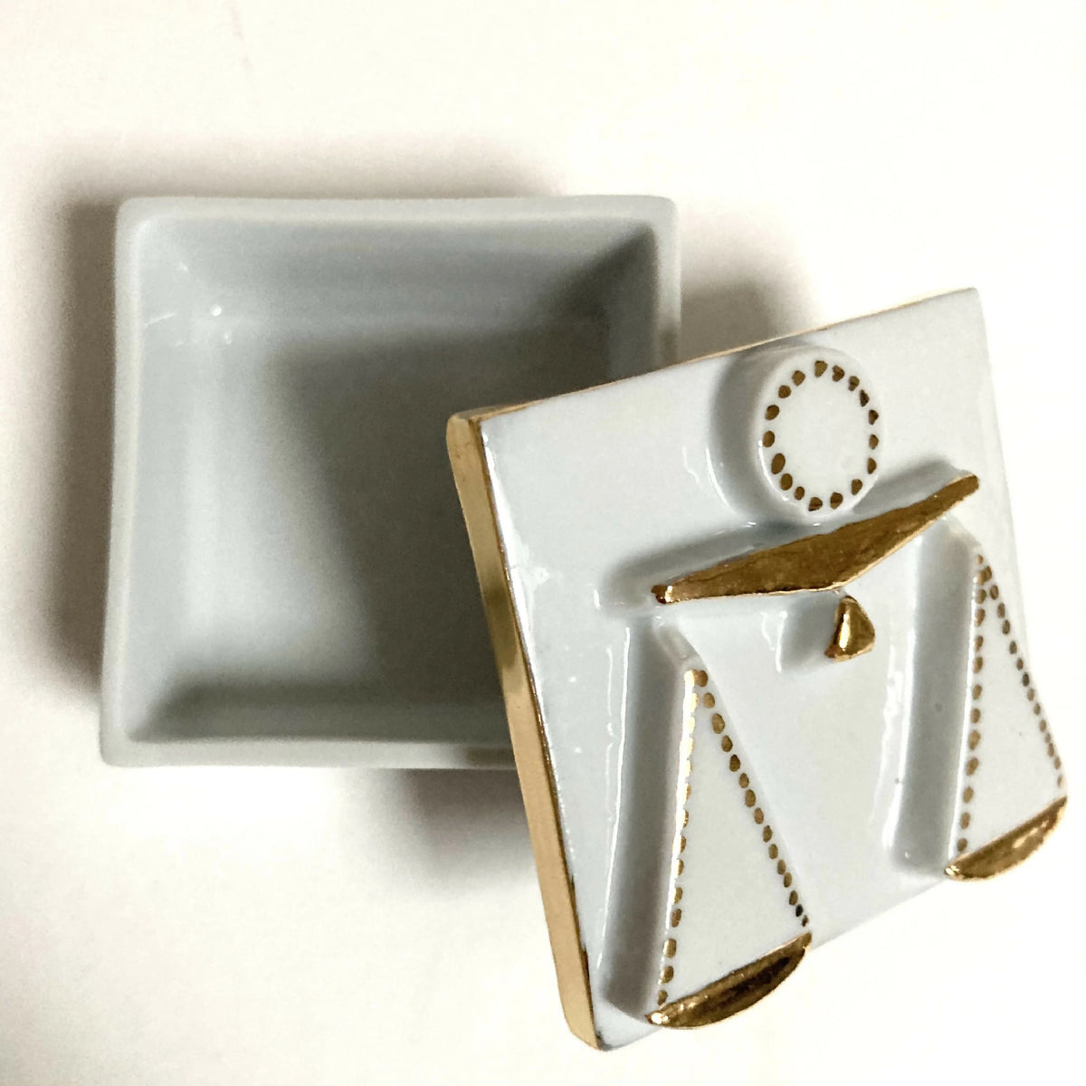 Boîte à bijoux en porcelaine blanche, motif balance doré, vue de côté du couvercle.