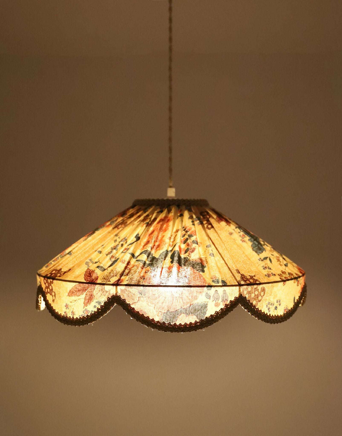 Abat-jour suspendu à motif floral, bord festonné et lumière visible à travers le tissu