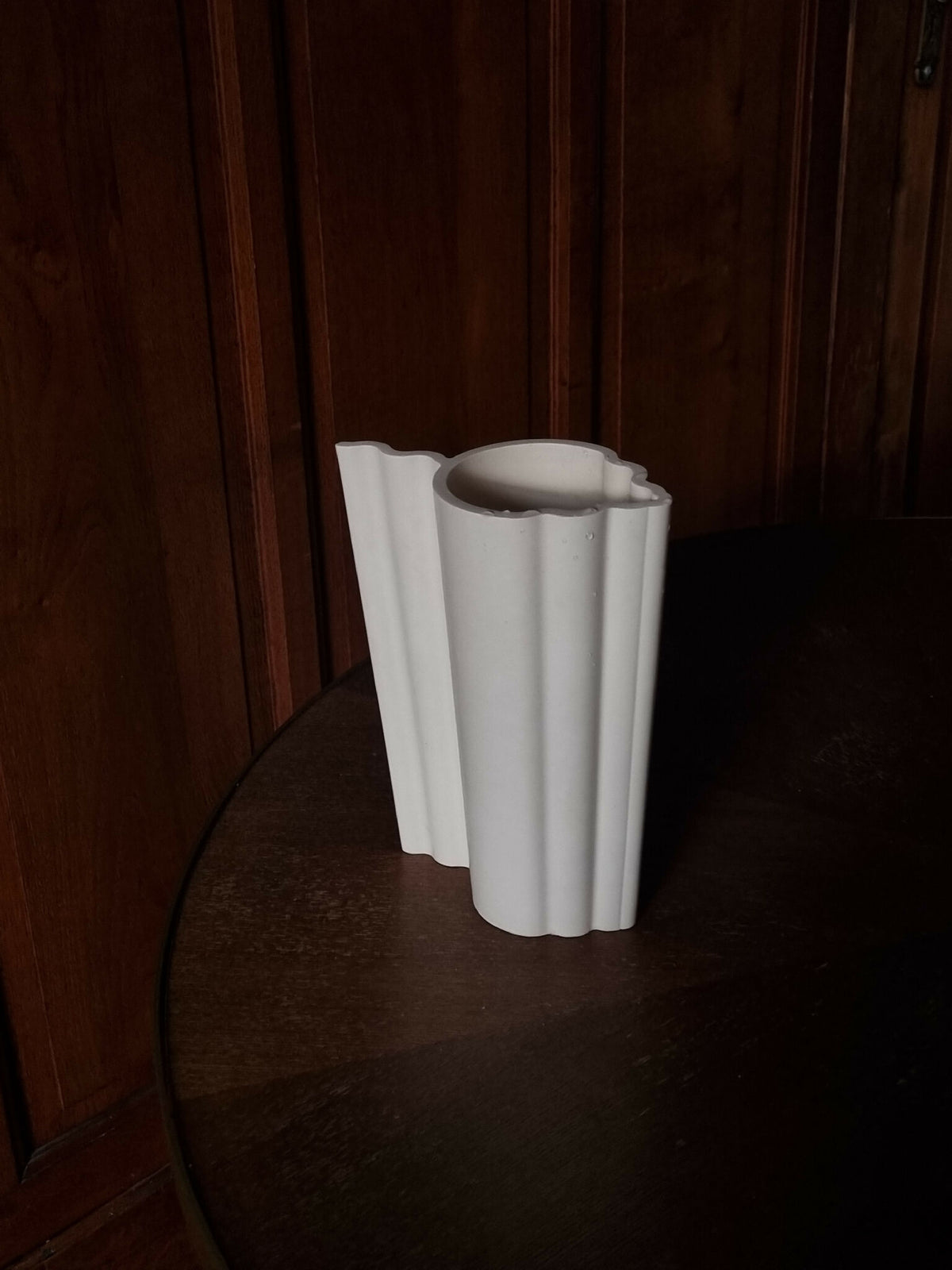 Vase blanc nervuré, côtés droits et bord supérieur ondulé, vue de profil.
