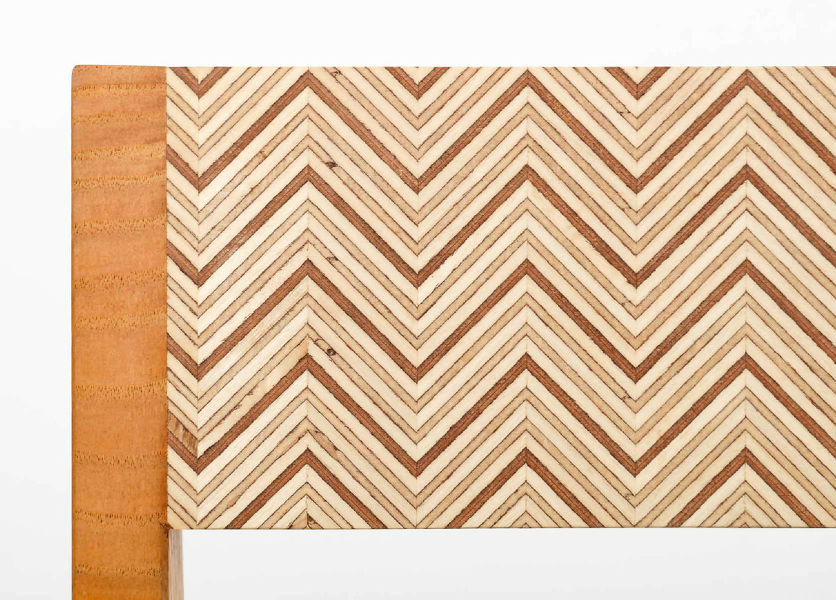 Détail du dossier de chaise : tissu beige à motif chevrons, bordure en bois.