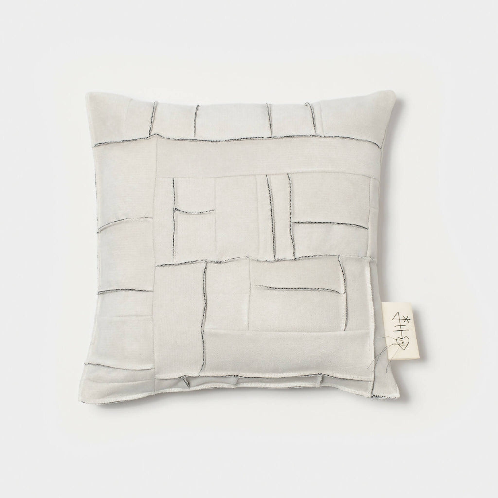 Coussin carré ivoire à motifs géométriques en relief et surpiqûres, face avant.