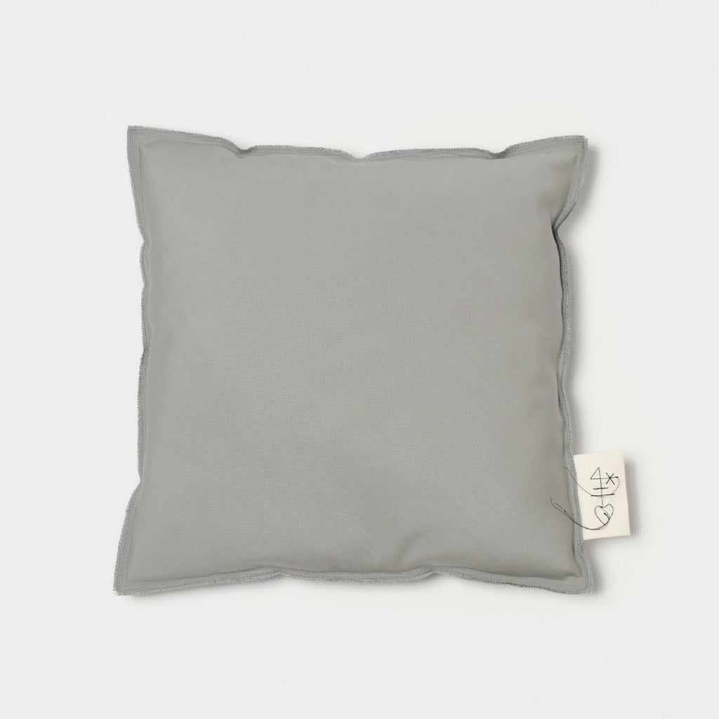 Coussin carré gris clair à housse lisse, vue de face avec étiquette