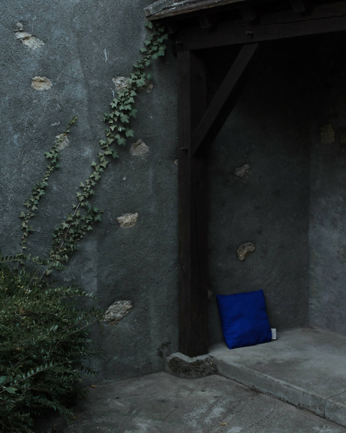 Coussin bleu dans une niche murale sombre, étiquette visible sur le côté