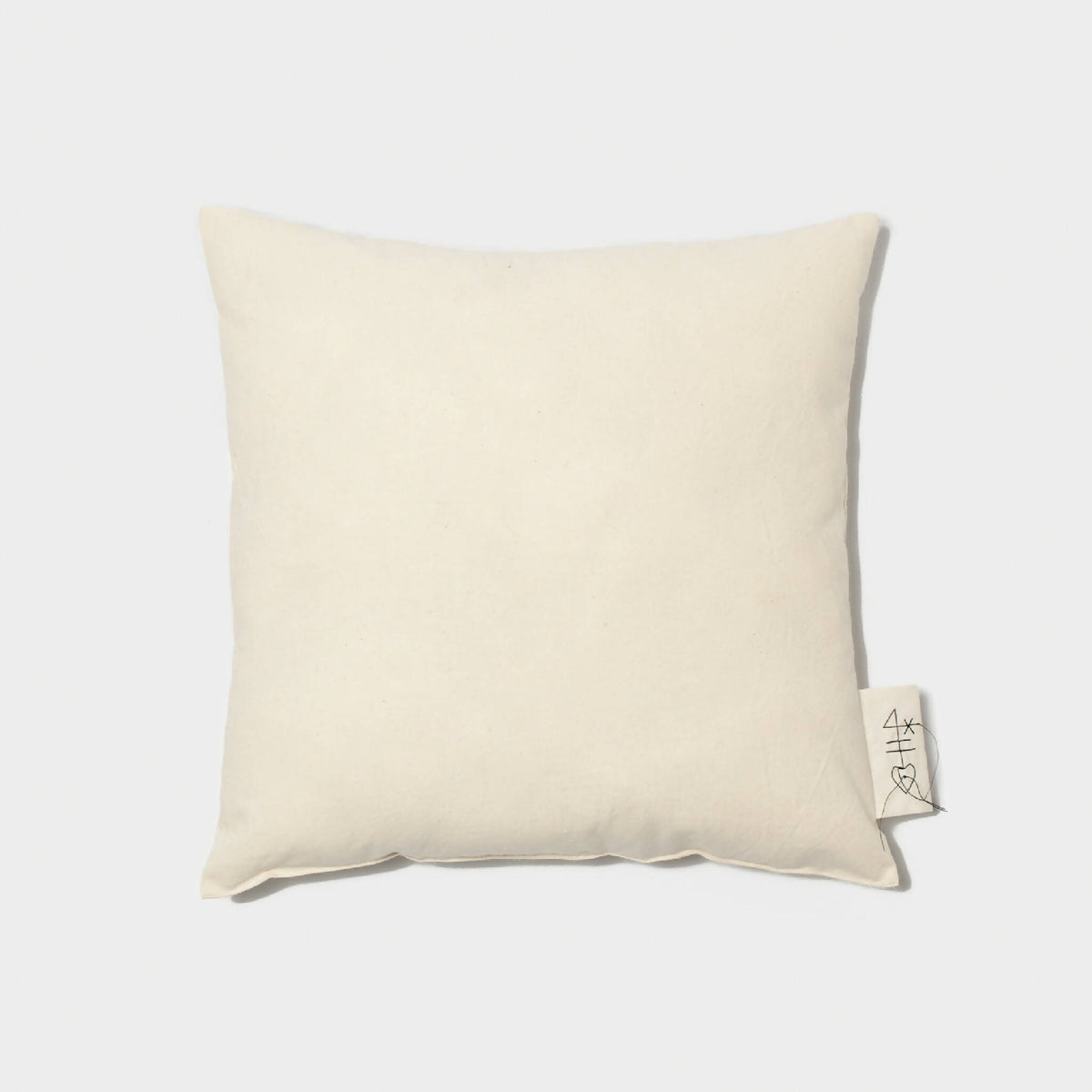 Coussin carré uni beige, coins arrondis, étiquette latérale