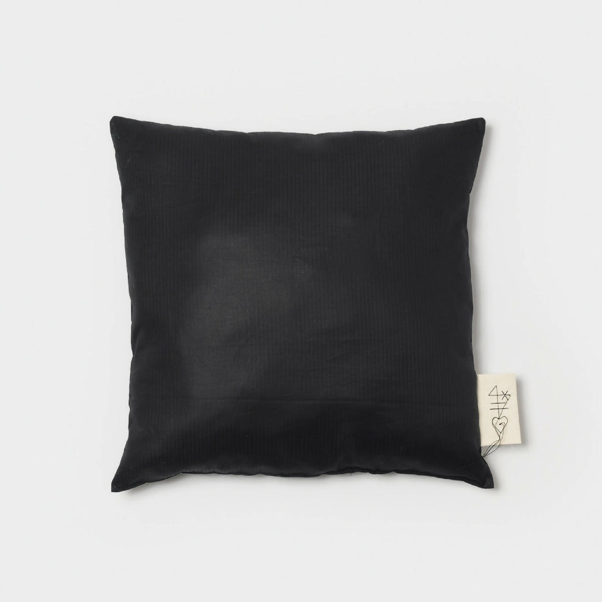 Coussin carré noir texturé avec étiquette sur le côté