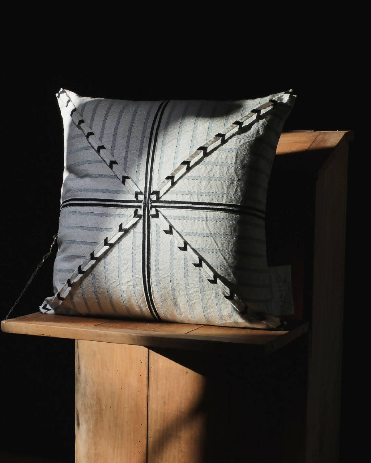 Coussin rectangulaire beige et bleu-gris, flèches noires sur rayures, vue de face.