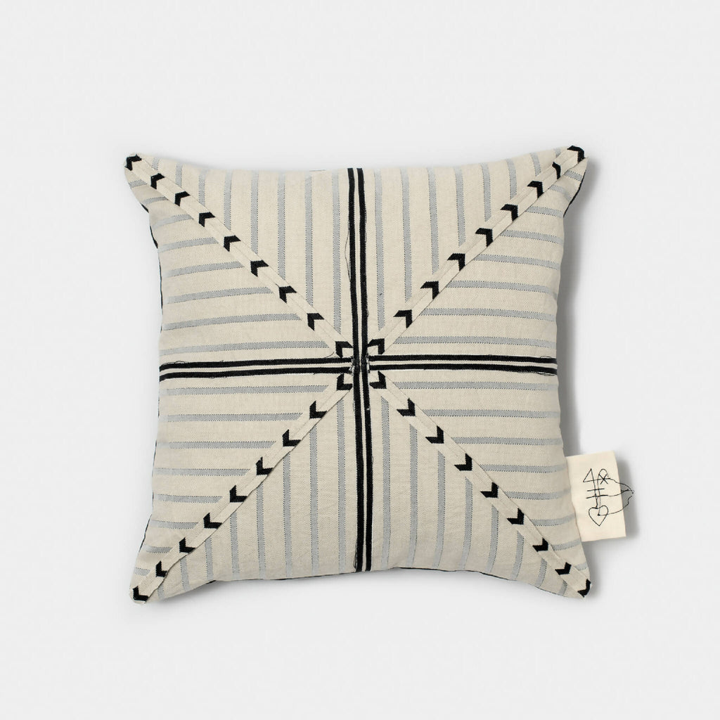 Coussin en tissu beige, rayures bleu-gris et flèches noires, étiquette latérale.