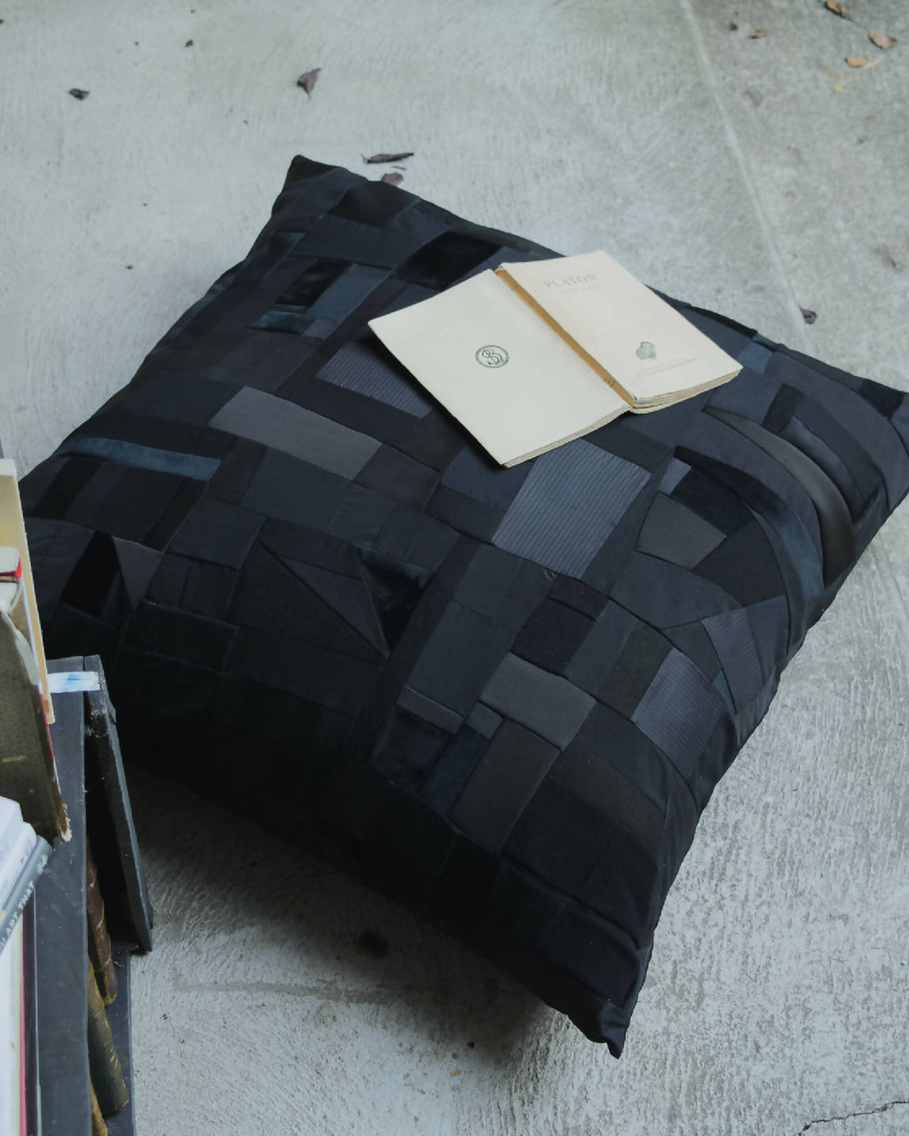 Coussin noir en patchwork géométrique, faces matelassées, forme rectangulaire