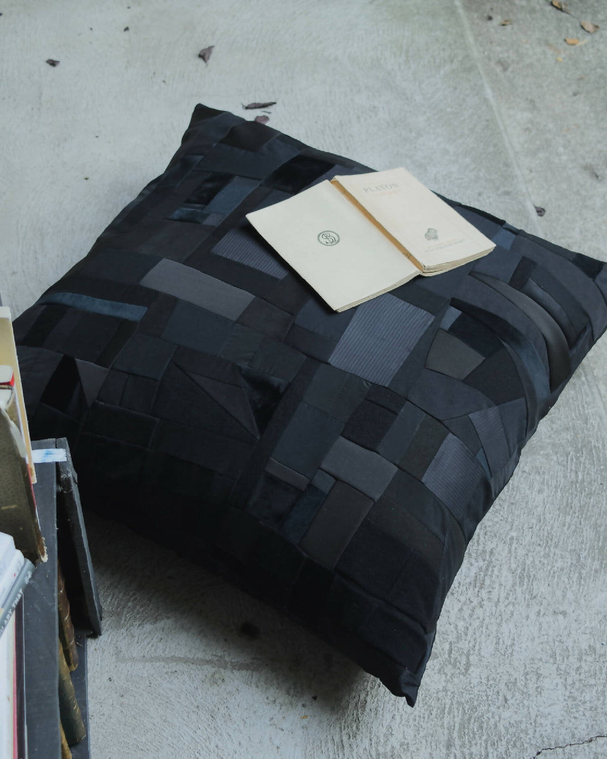 Coussin noir en patchwork géométrique, faces matelassées, forme rectangulaire