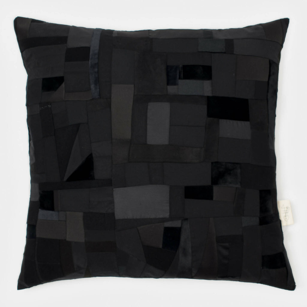 Coussin rectangulaire noir en patchwork de carrés et losanges, aspect matelassé