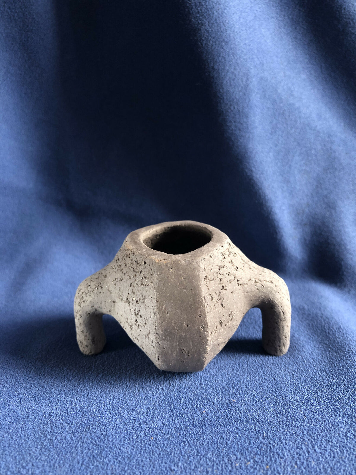 Petit pot en pierre grise, anses latérales, ouverture ronde au sommet.