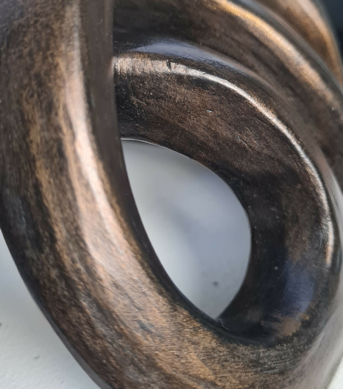 Détail de sculpture abstraite : anneaux métalliques sombres et reflets cuivrés