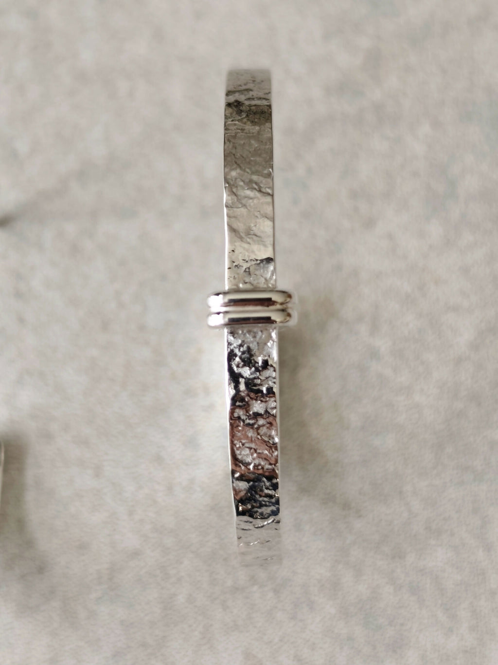 Boucle d’oreille courbe argentée martelée, serti horizontal et fermoir à l’arrière