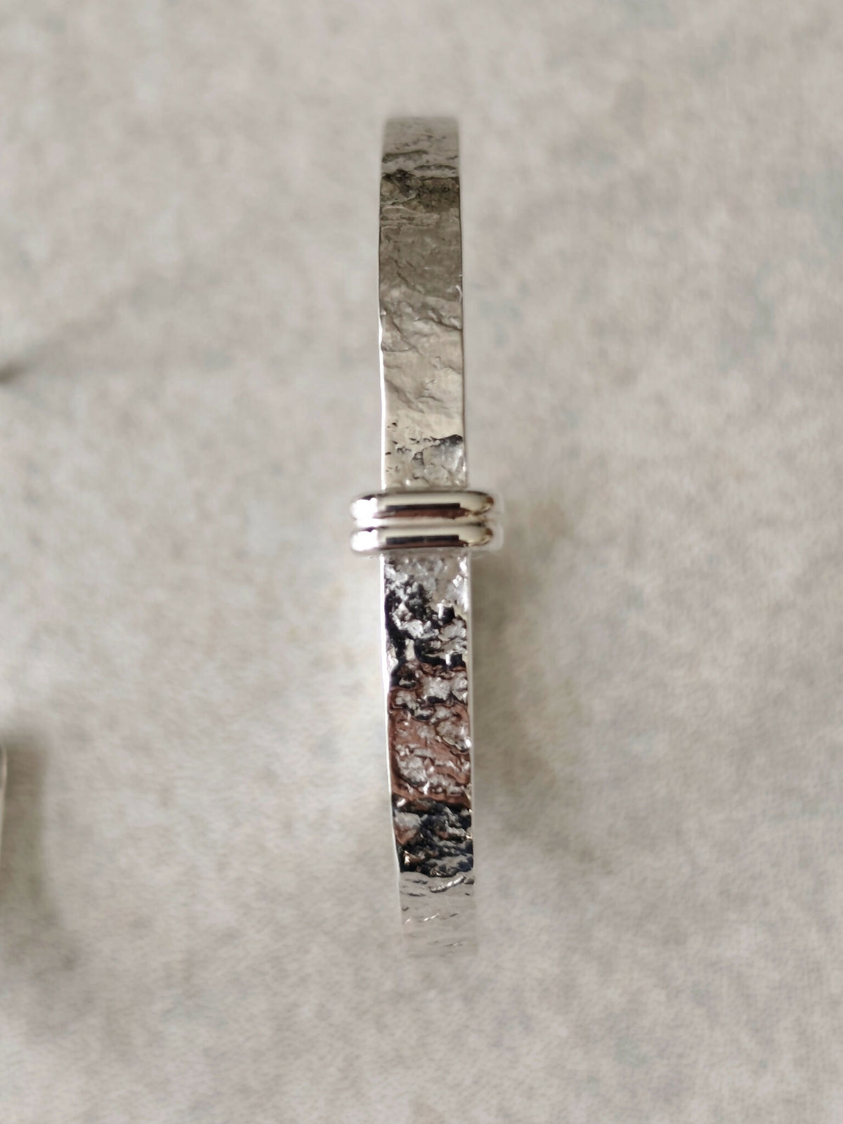 Boucle d’oreille courbe argentée martelée, serti horizontal et fermoir à l’arrière