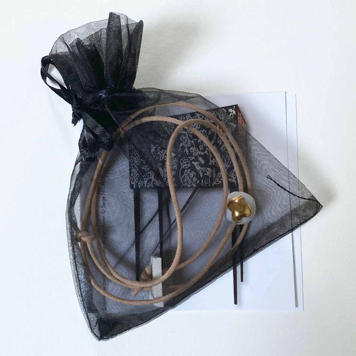 Collier en porcelaine dans un sachet en organza noir, pendentif goutte dorée.