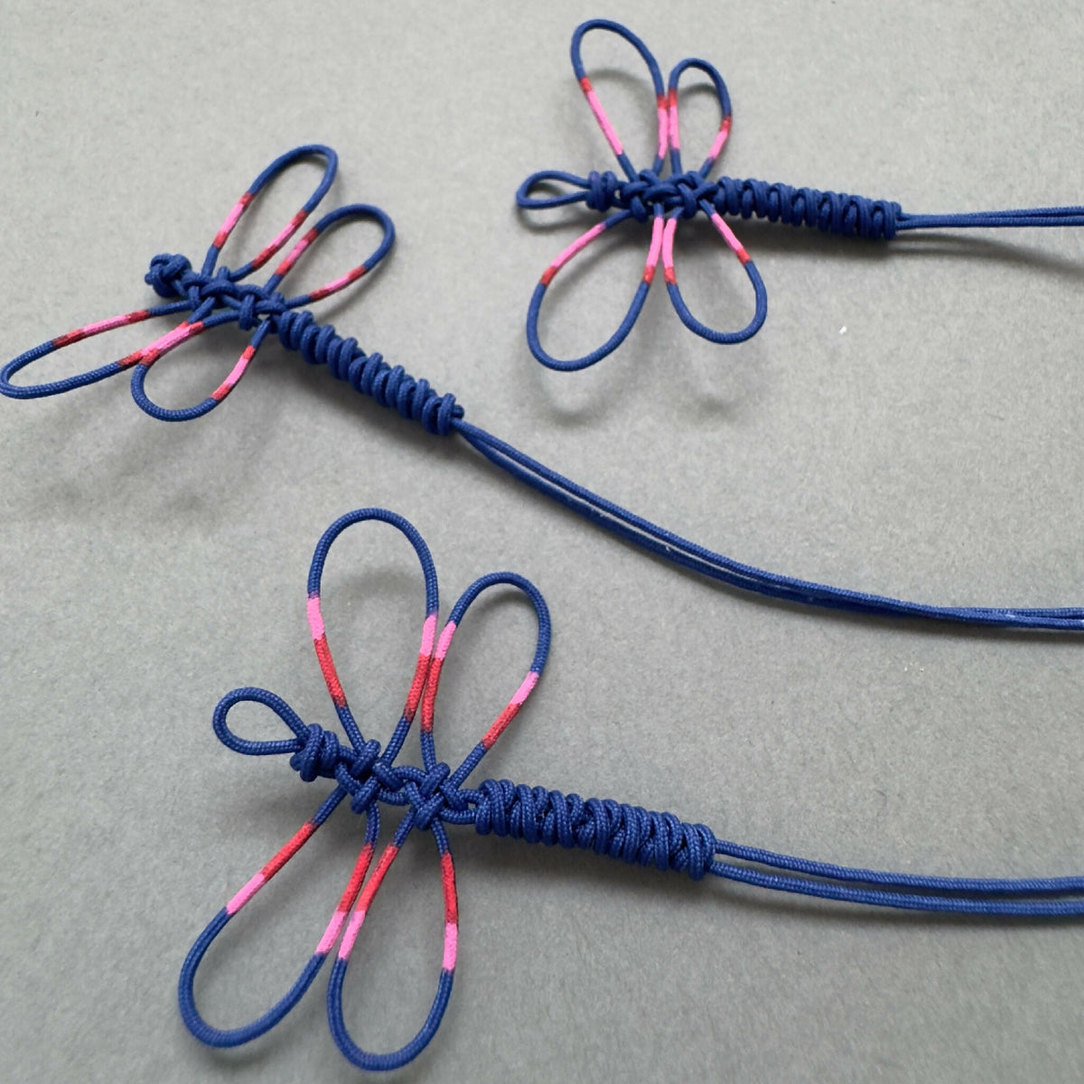 Bracelets fins bleus avec motifs de libellules rose, cordon bleu et attaches torsadées.