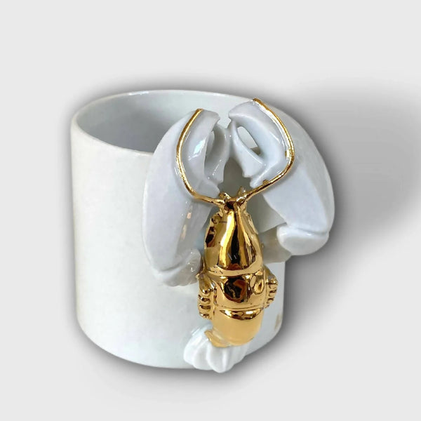 Tasse blanche avec figurine de homard doré sur l’anse