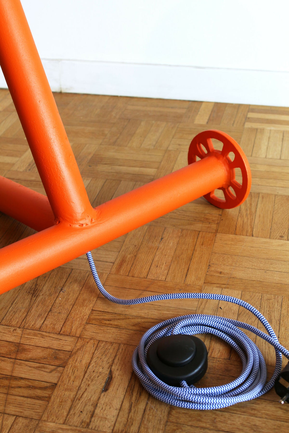 Lampe UMARELL Enrico orange : gros plan du pied avec câble et bouton au sol