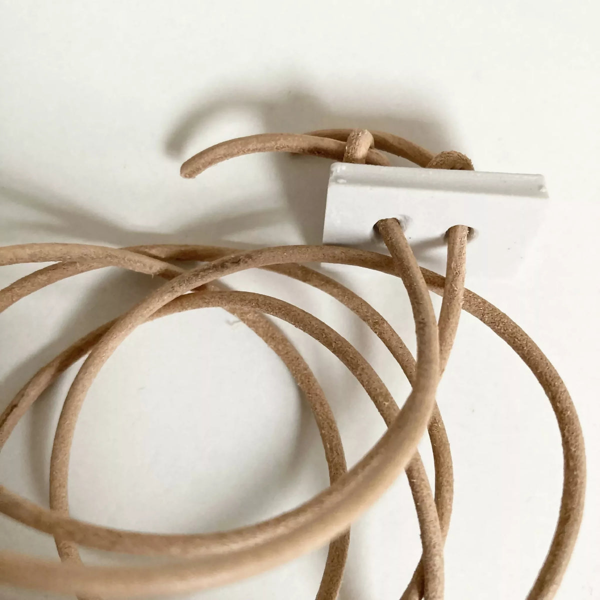Cordon de pendentif : cordons en cuir beige et étiquette blanche, vue rapprochée
