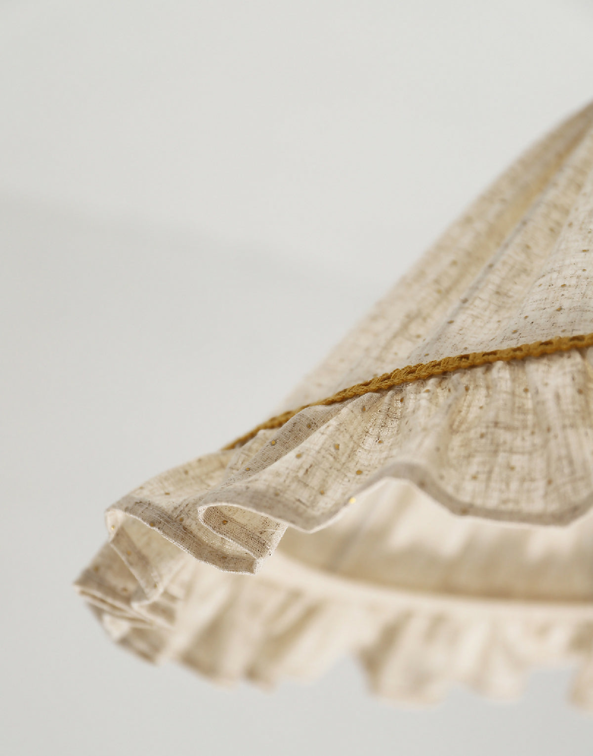 Détail du volant de l’abat-jour conique en lin et coton beige avec liseré doré
