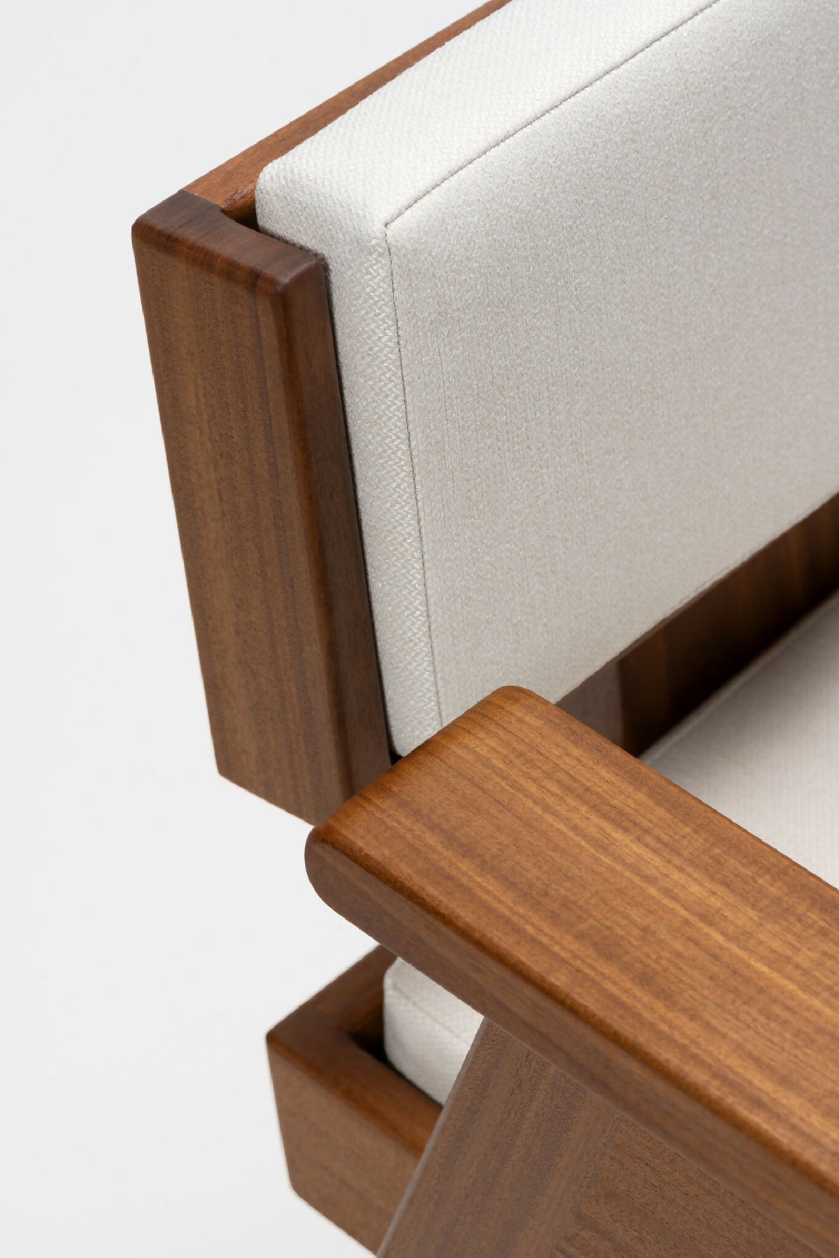 Fauteuil en bois clair, accoudoirs rectangulaires et coussin blanc, vue de côté