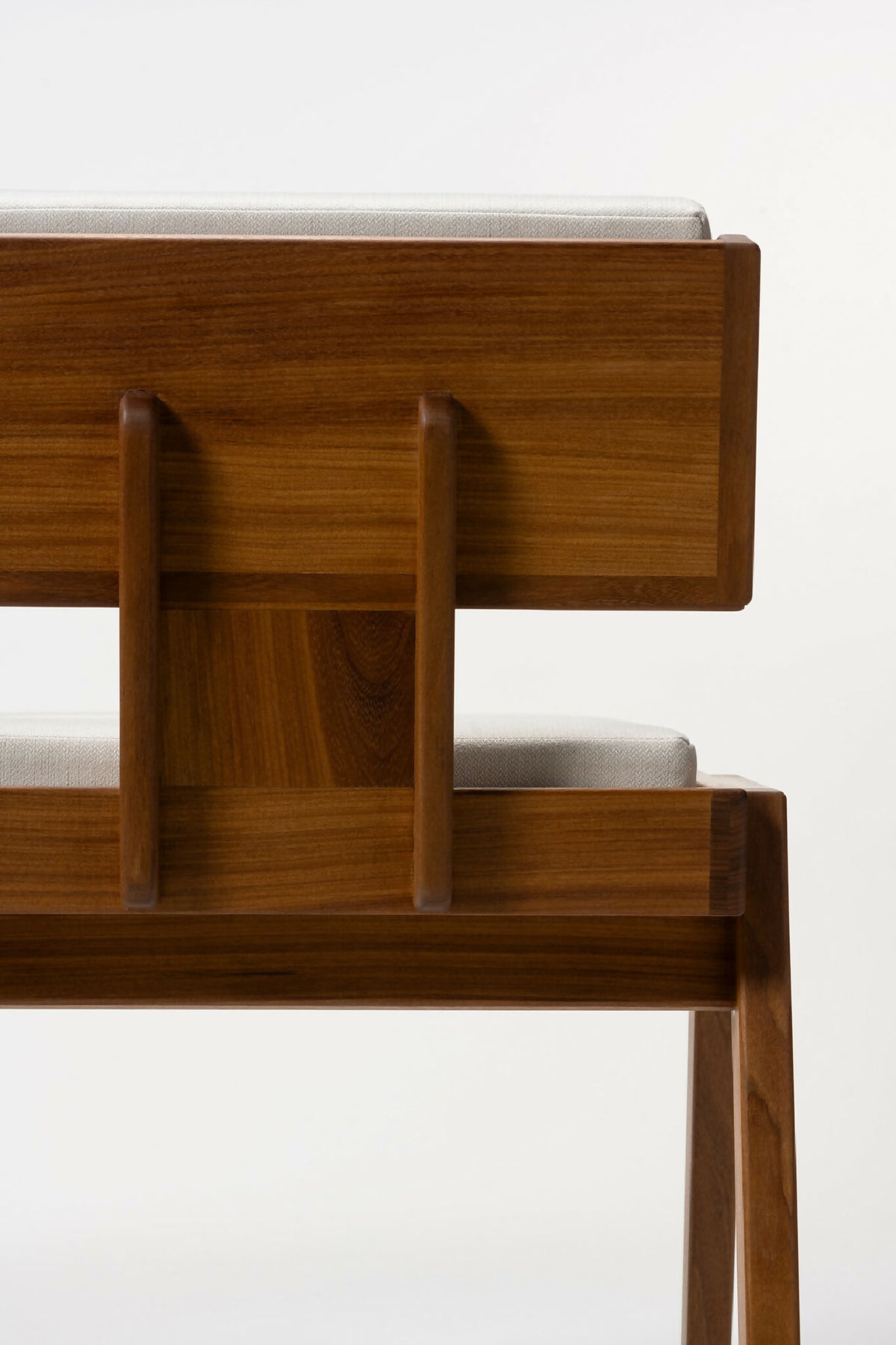 Fauteuil en bois clair, dossier à panneaux verticaux et coussins blancs, vue arrière