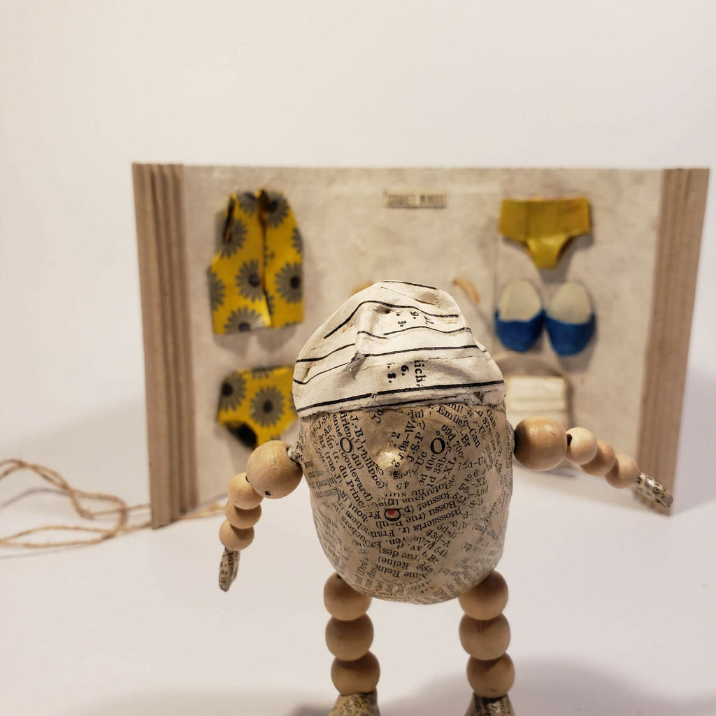 Sculpture Coquet minois : figurine en tissu beige, avec accessoires jaunes et bleus