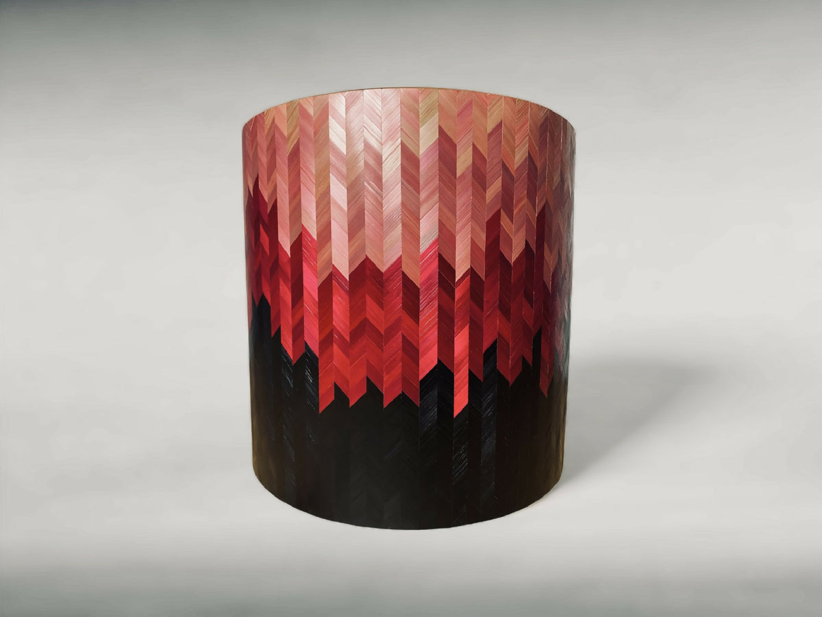 Bout de canapé rond à motif chevrons rouge et beige, dessus beige, base sombre.