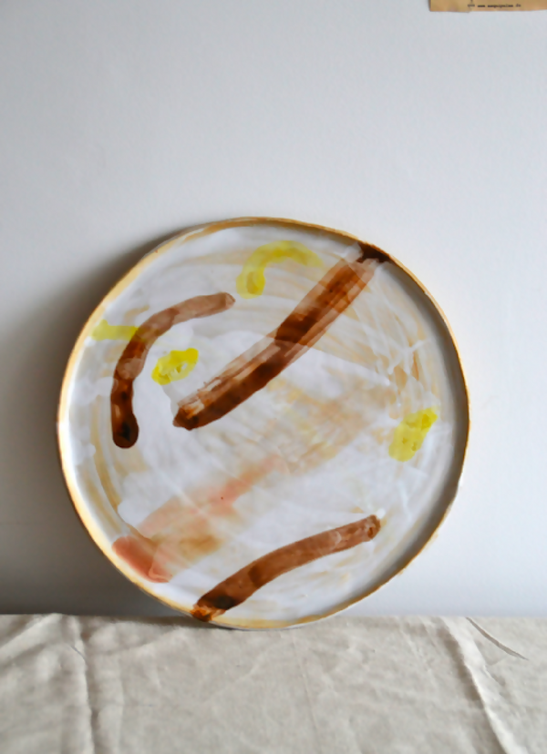 Plateau rond à motifs abstraits, fond blanc cassé, jaune et brun