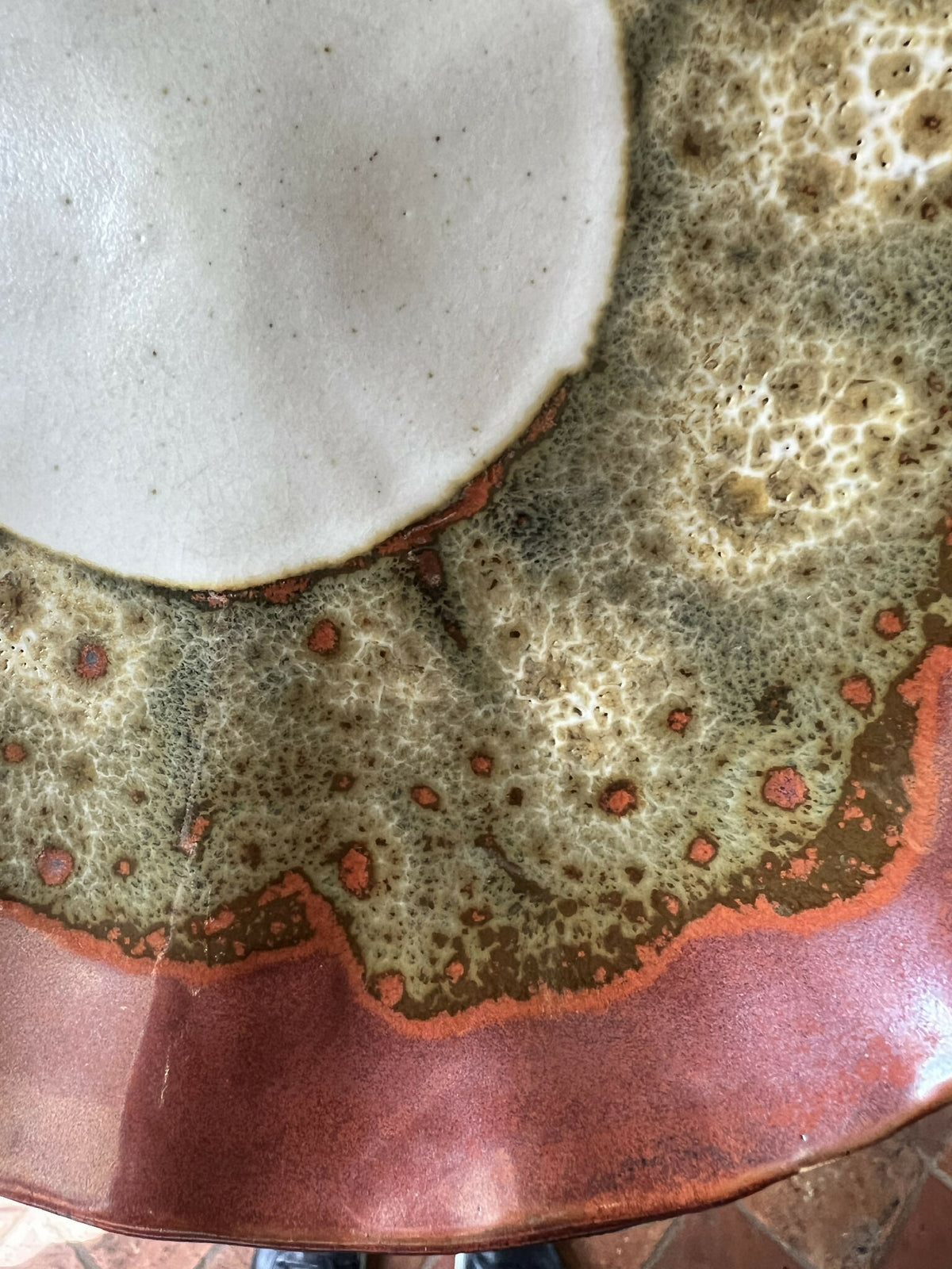 Assiette Prunelle bord brun, détail du décor vert moucheté et points rouges sur émail.