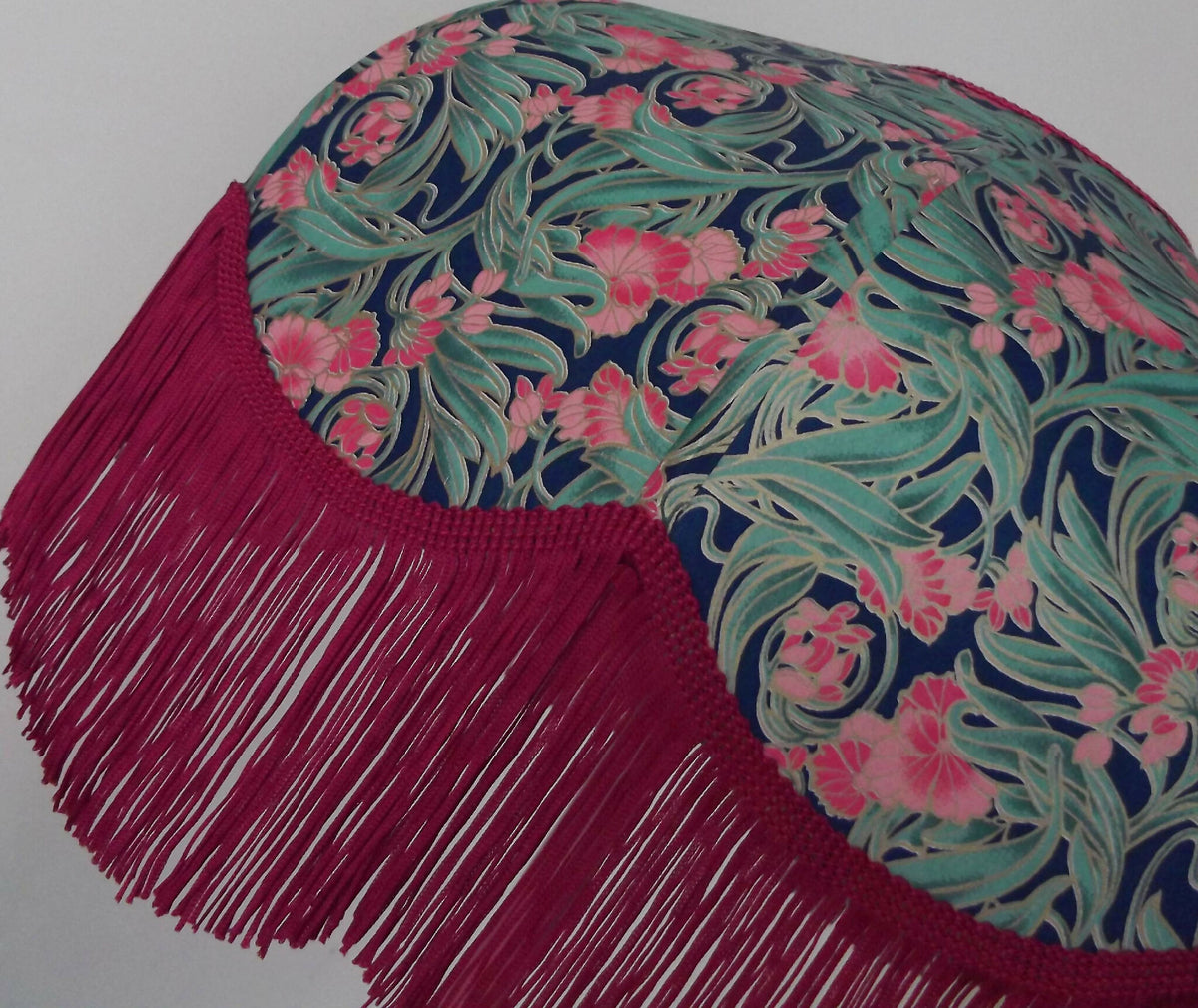 Abat-jour rétro gros plan : papier fleuri bleu-vert et rose, franges bordeaux