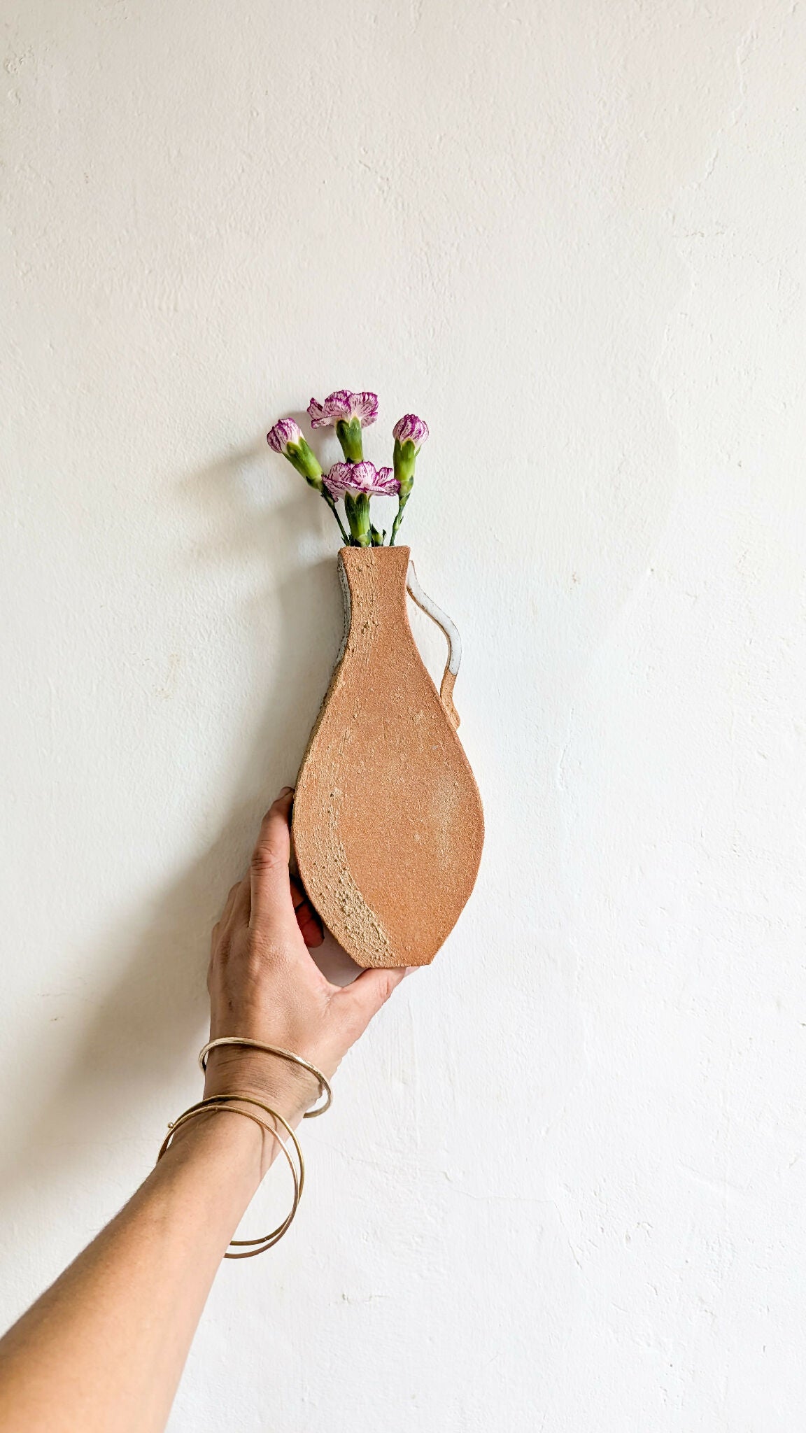 Vase mural en terre cuite vu de profil, cordon de fixation, bouquet violet