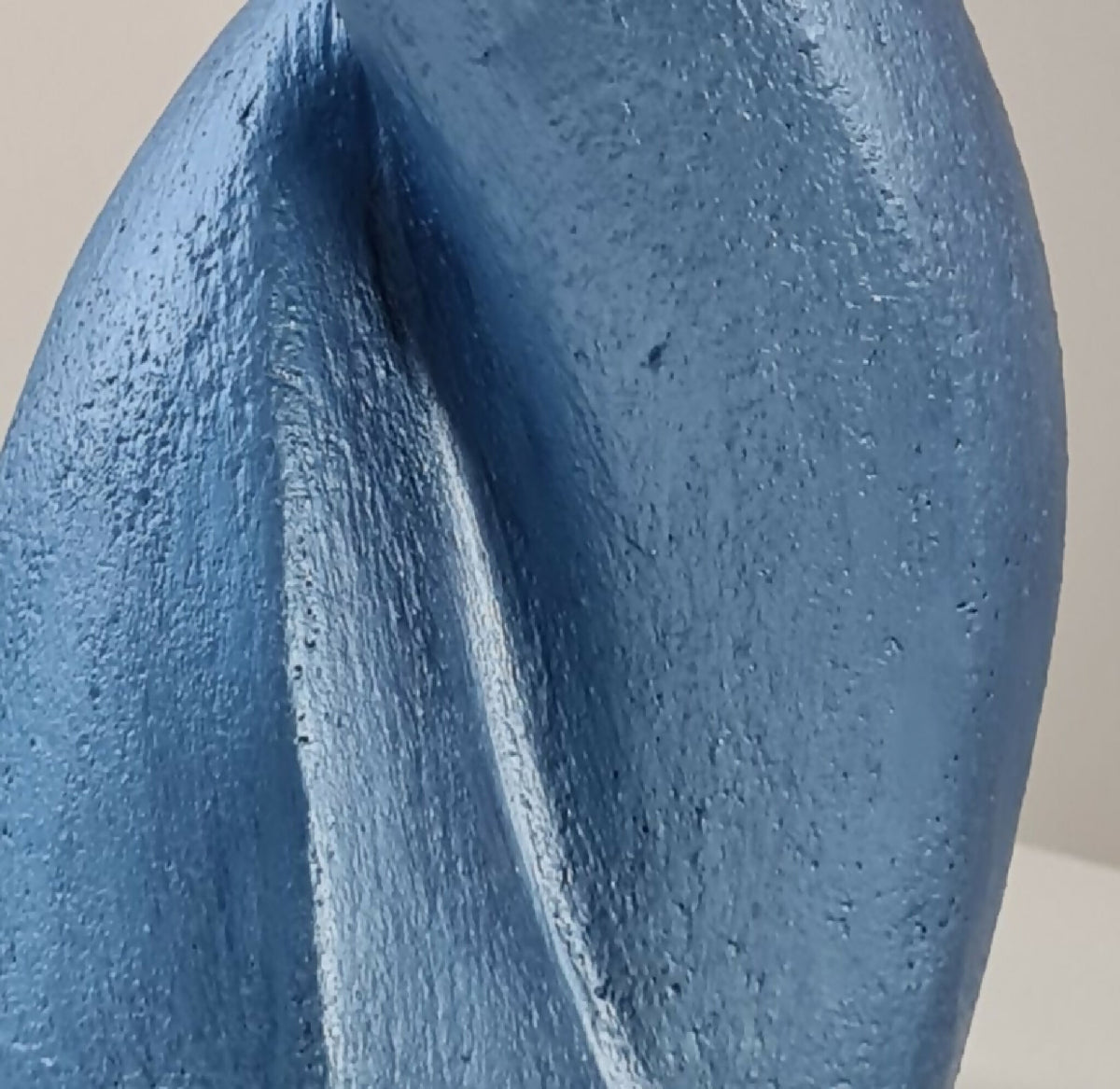 Sculpture de couple bleue, détail des corps lisses et texture mouchetée