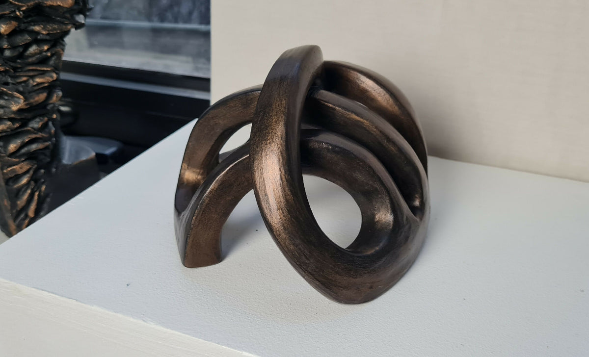 Sculpture abstraite en métal sombre, entrelacs en anneaux, vue latérale