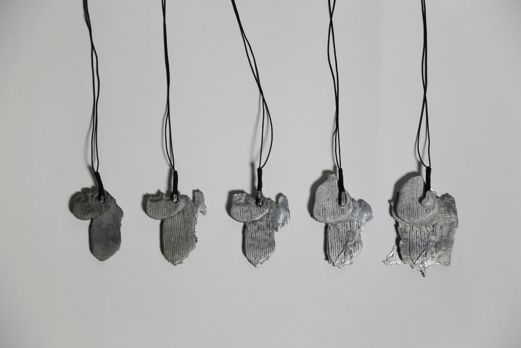 Lot de pendentifs gris en forme de feuille d’arbre, sur cordons noirs.