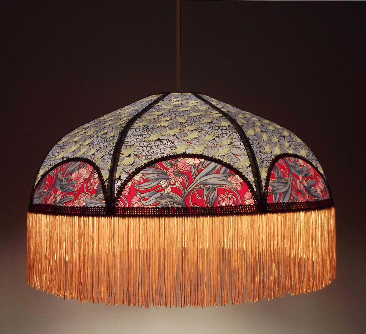 Suspension rétro ronde avec franges dorées et motifs japonais rouge, gris et crème.