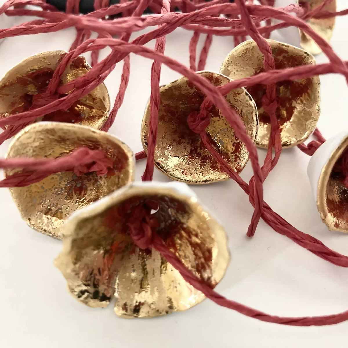 Collier : gros pendentifs fleurs dorées sur fils rouges, détail en gros plan