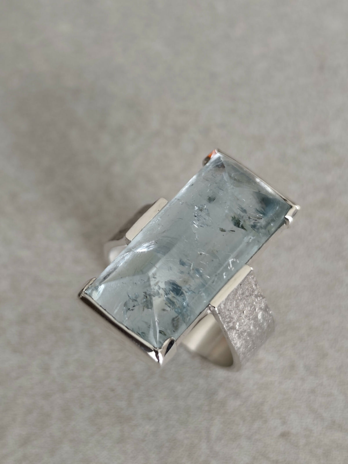 Bague en topaze bleu clair rectangulaire, monture argent, gros plan.