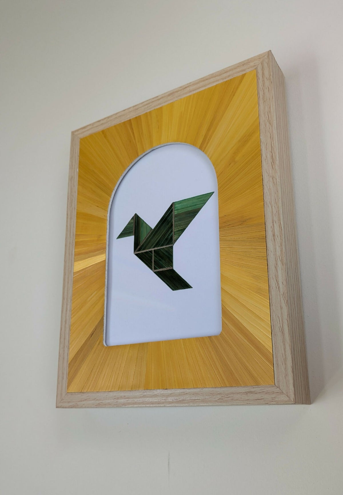 Tableau encadré en bois clair, motif géométrique vert dans une forme blanche